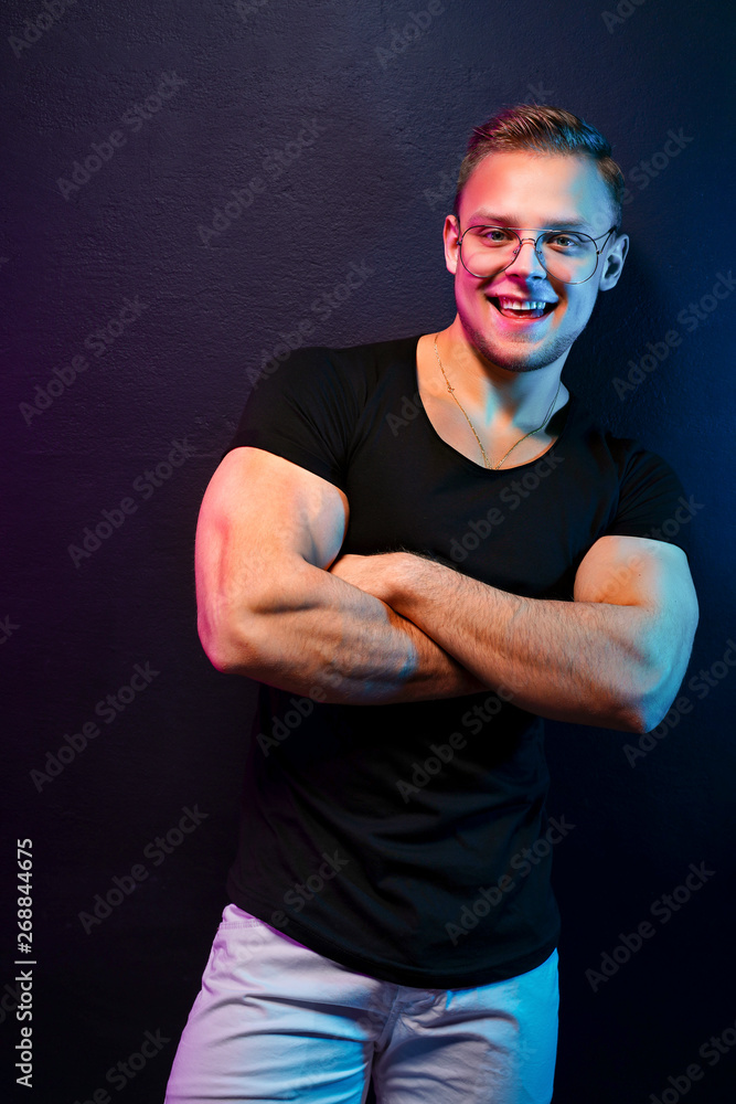 Confident guy in trendy outfit posing under colorful illumination during party. Confident guy in trendy outfit posing under colorful illumination during party.