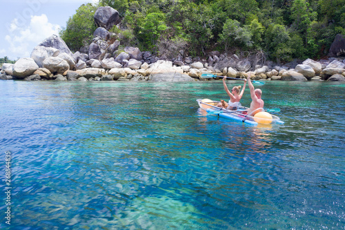 Aerial drone view of couple with dog in kayak on amazing crystal clear sea water. Tropical vacation, travel with pet concept