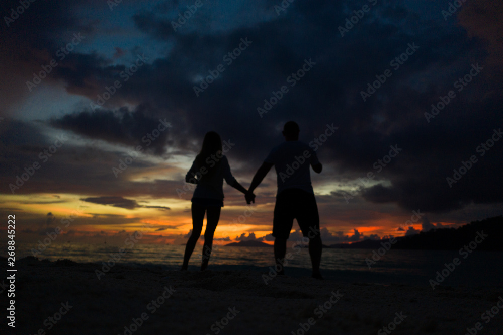 Couple holding hands on the beach over sea and beautiful gold sunset sky background. Romantic travel holiday concept