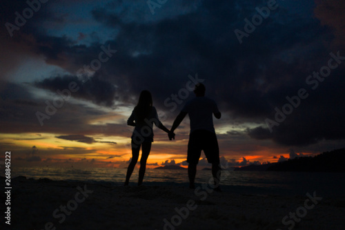 Couple holding hands on the beach over sea and beautiful gold sunset sky background. Romantic travel holiday concept