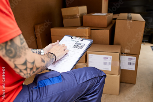 Delivery man with clipboard checking delivery note.