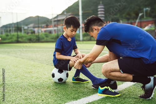 Father helping son dressing up in soccer uniform photo