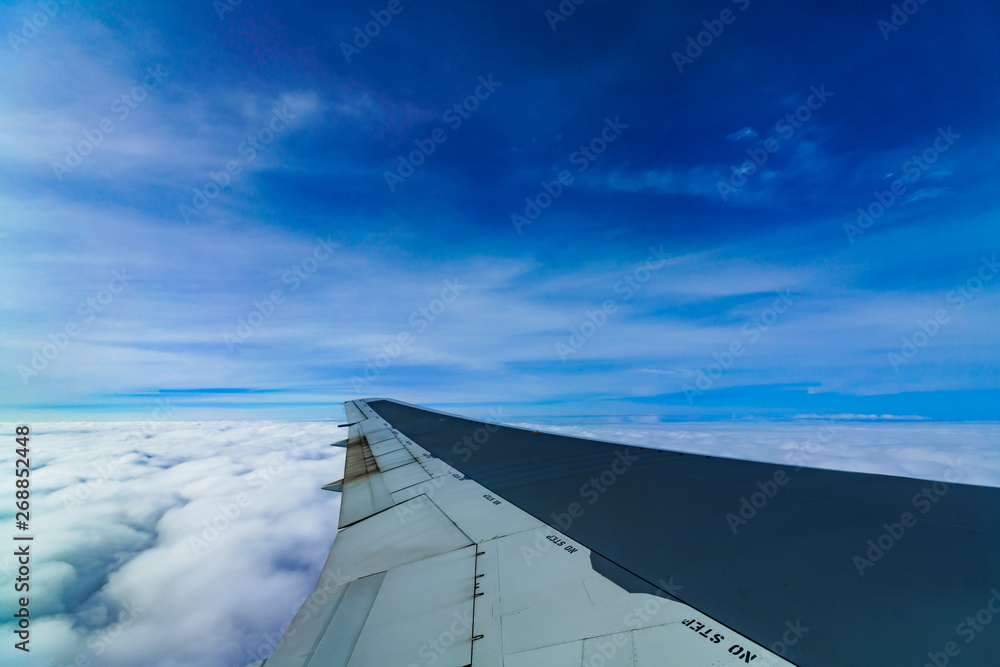 Clouds and sky and wing as seen through window of an aircraft