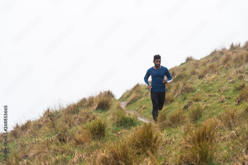 Man cross country running along a track in the mountains. Man cross country running along a track in the mountains.