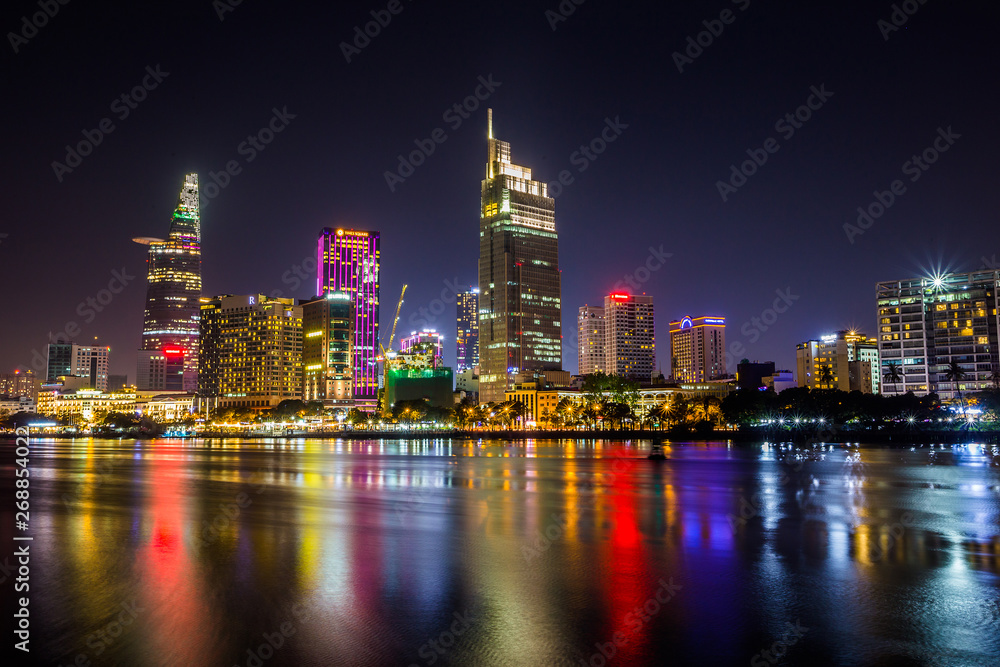 Obraz premium Ho Chi Minh City, Vietnam - May 7, 2019 : Riverside City at nightclouds in the sky at end of day brighter coal sparkling skyscrapers along beautiful river in Ho Chi Minh City, Vietnam - Image