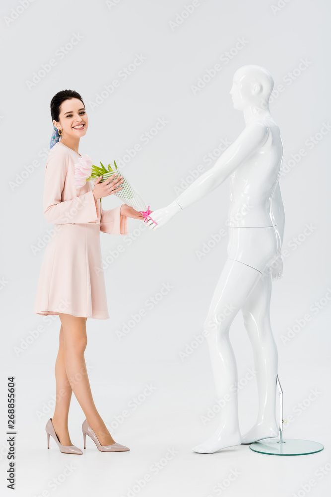 beautiful smiling girl with mannequin and flower bouquet isolated on grey beautiful smiling girl with mannequin and flower bouquet isolated on grey