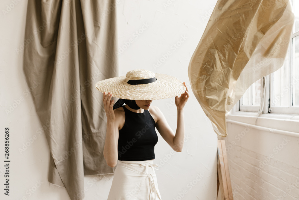 fashion model standing in studio scene with layered fabrics draped and moving in wind