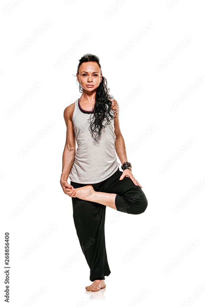 Fototapeta premium Portrait of young woman standing on one leg while practicing yoga