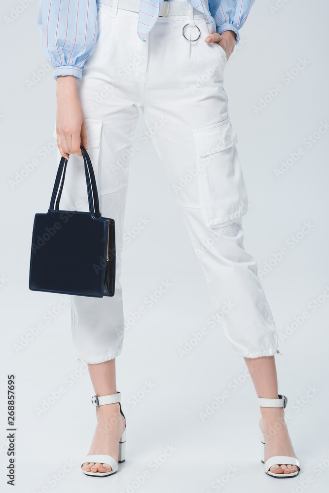 partial view of stylish girl with bag posing on grey partial view of stylish girl with bag posing on grey