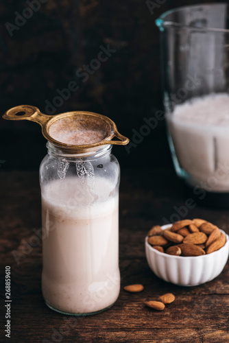 Food: Almond milk in a bottle with some almonds besides and blen photo