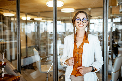 Portrait of a young and cherful business woman standing with laptop in the office photo