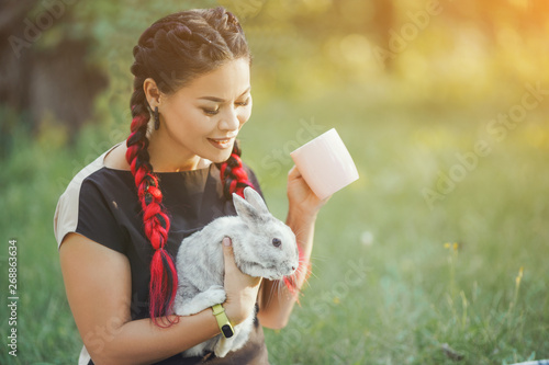 Pretty Girl With Hair Braiding Huggs a Rabbit on Beautiful Summer Nature photo