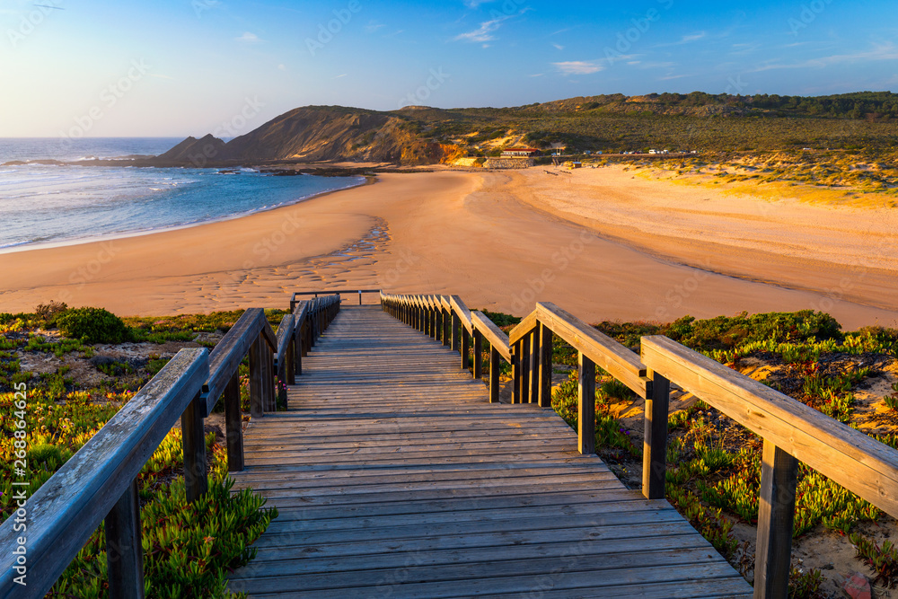 Obraz premium Wooden walkway to the beach Praia da Amoreira, District Aljezur, Algarve Portugal. Panorama from Amoreira beach in the Algarve Portugal. Beach and estuary of the Aljezur river, Praia da Amoreira.