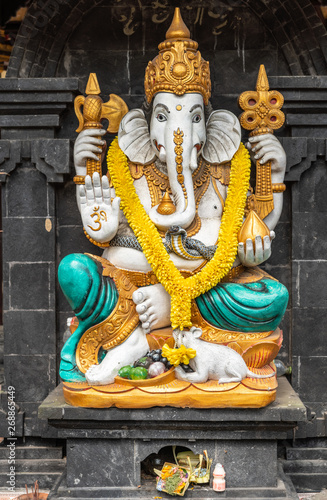 Bali, Indonesia - February 25, 2019: Ulun Danu Beratan Temple in Bedoegoel. Closeup of colorful Ganesha shrine on entrance checkpoint. Gold, white, azure and yellow against black stone. photo