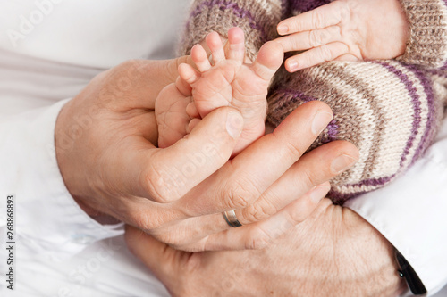 Baby feet in father hands. Tiny Newborn Baby's feet on male hands closeup. Dad and his child. Happy Family concept. Beautiful conceptual image of parenthood