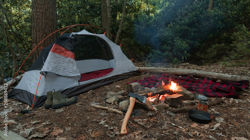 Camping tent in the Blue Ridge Mountains in Asheville, North Carolina. Outdoor lifestyle with axe, cast iron skillet, flannel blanket. Rustic Bushcraft Campsite. Survival shelter in the wilderness. 