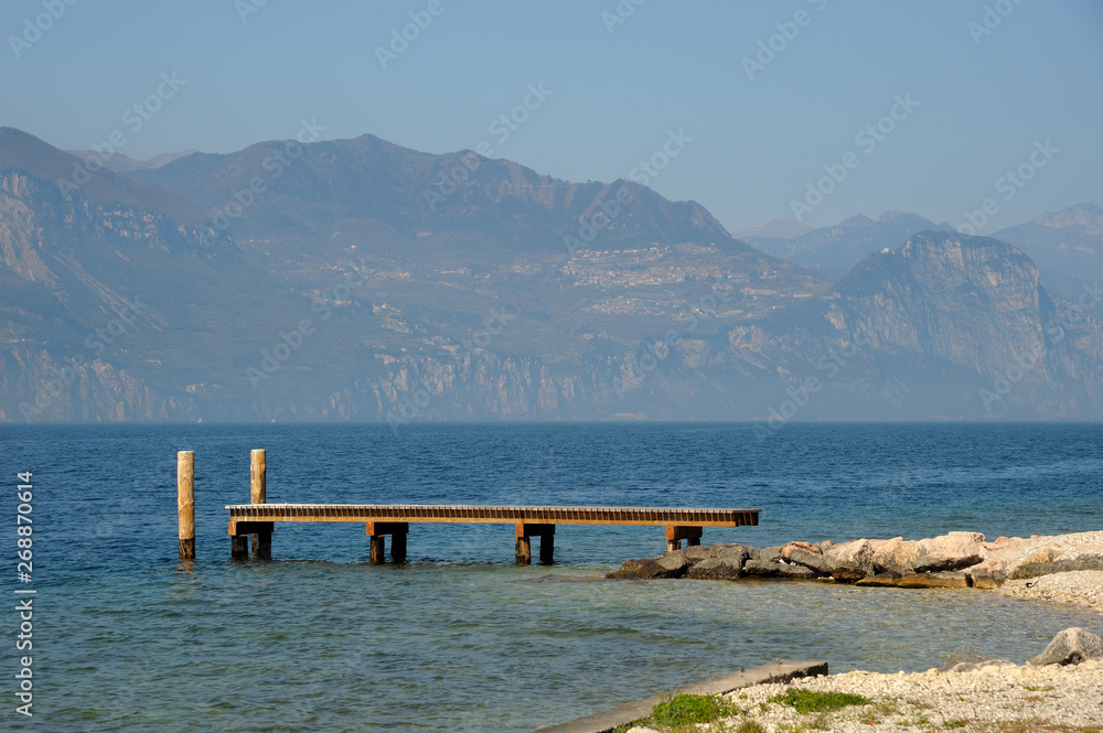 Pier on the Garda lake, blue water and mountain Pier on the Garda lake, blue water and mountain