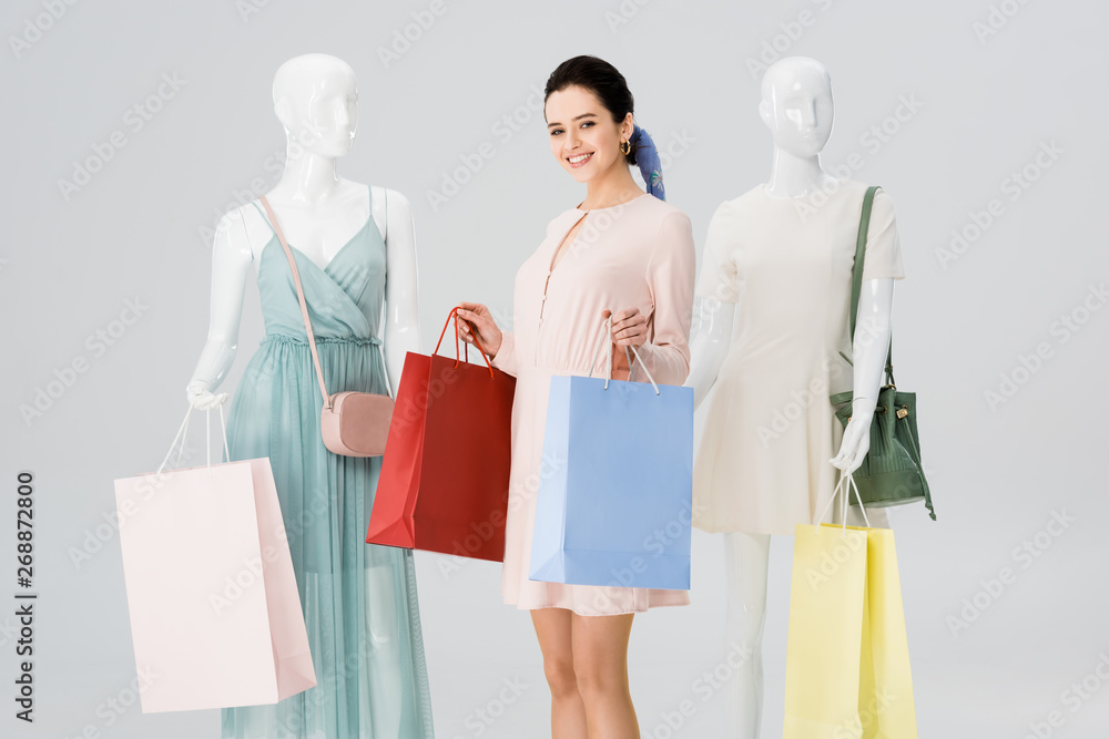 beautiful smiling girl with shopping bags near mannequins isolated on grey beautiful smiling girl with shopping bags near mannequins isolated on grey