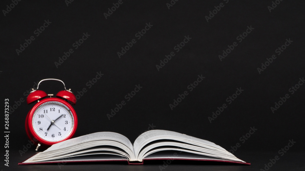 red alarm clock and open book on black background, isolated. back to school red alarm clock and open book on black background, isolated. back to school