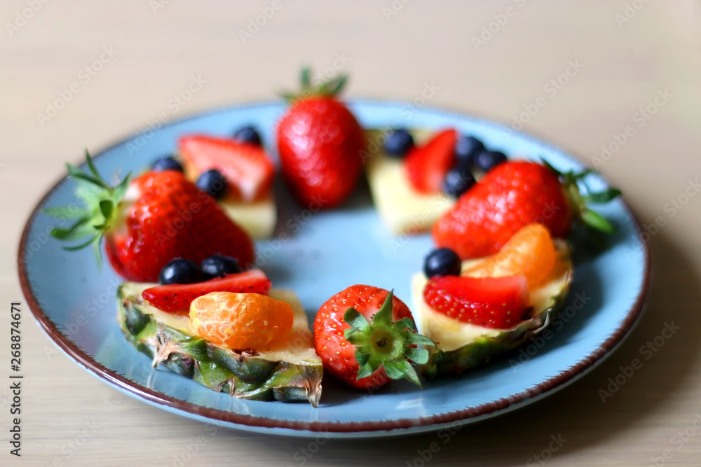 Various spring fruit on a turquoise plate: strawberries, pineapple, blueberries and tangerine. Selective focus. Various spring fruit on a turquoise plate: strawberries, pineapple, blueberries and tangerine. Selective focus.