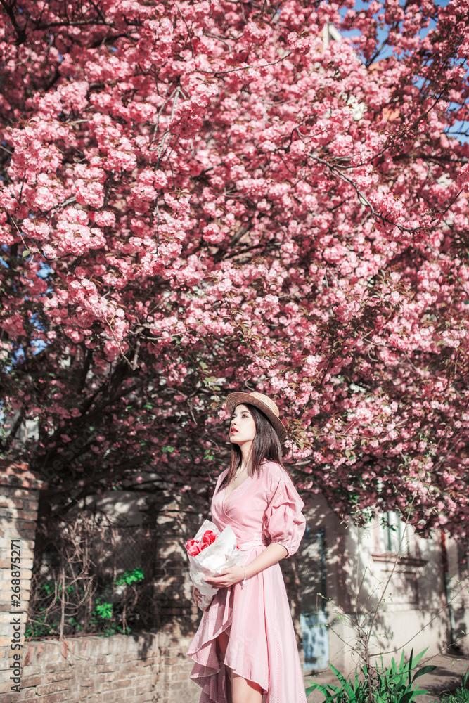 Young woman and sakura tree on the street Young woman and sakura tree on the street