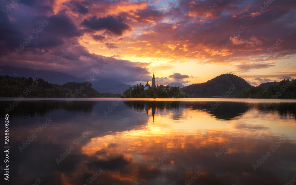 Obraz premium Dramatic sunrise on lake Bled, sunrise view on Bled lake, island, Pilgrimage Church of the Assumption of Maria and Castle with mountain range (Stol, Vrtaca, Begunjscica). Bled, Slovenia,
