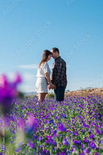 Loving couple among violet flowers in summer meadow