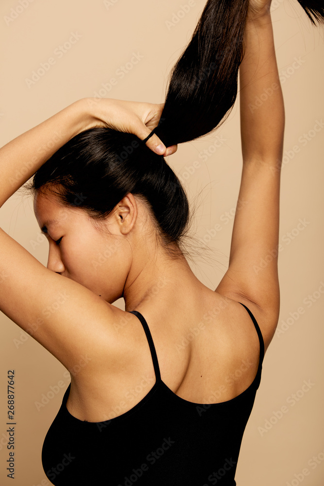 Young woman styling her hair and making ponytail Young woman styling her hair and making ponytail