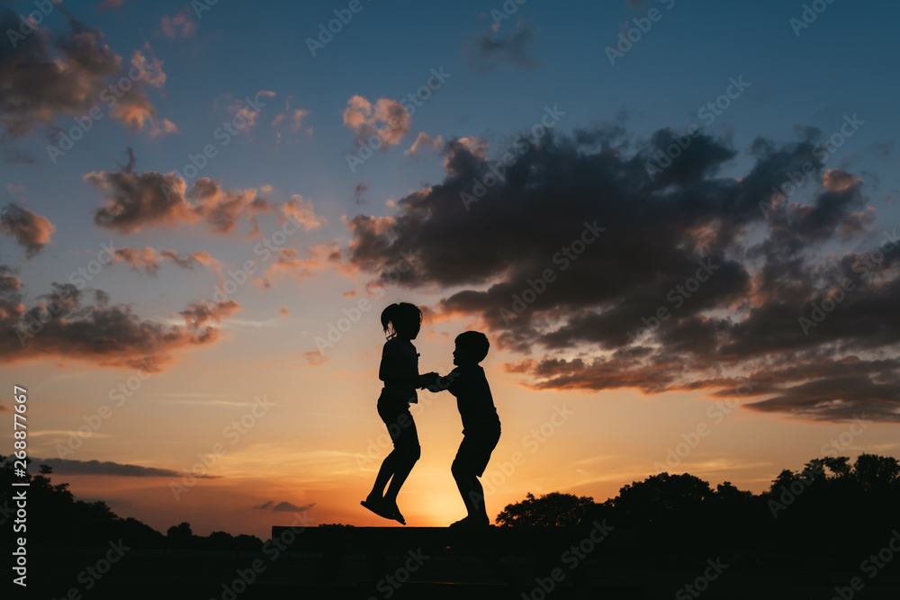 Two Kids Jumping Together At Sunset Two Kids Jumping Together At Sunset