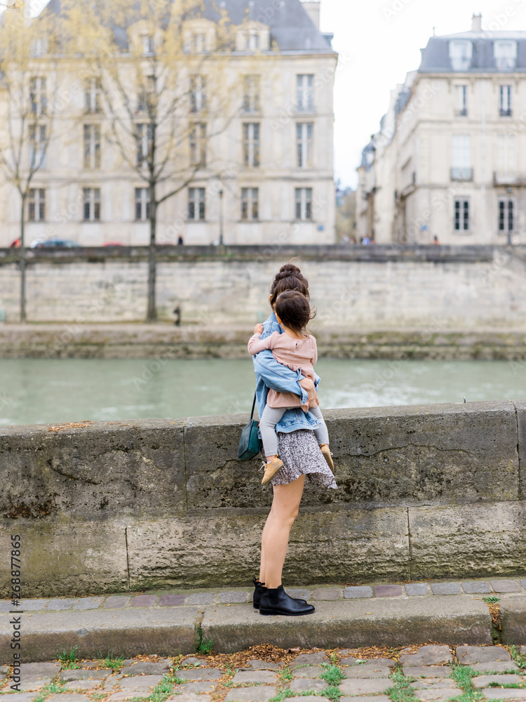 Mom holding baby in front of Seine River Mom holding baby in front of Seine River