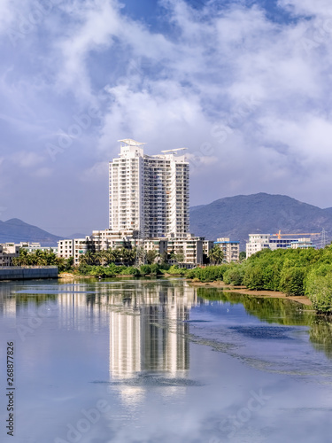 Apartment building reflected in a river on a summer day  Sanya  Hainan Island  China