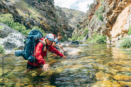 Hiker crossing mountain river