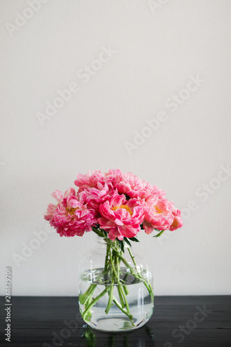 Wallpaper Mural large glass vase filled with coral charm peonies sitting on a black table Torontodigital.ca