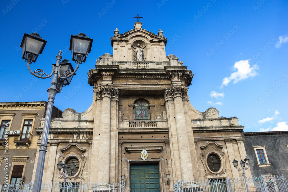 Catania baroque basilica, view of the historical facade, statues, columns and street lamp