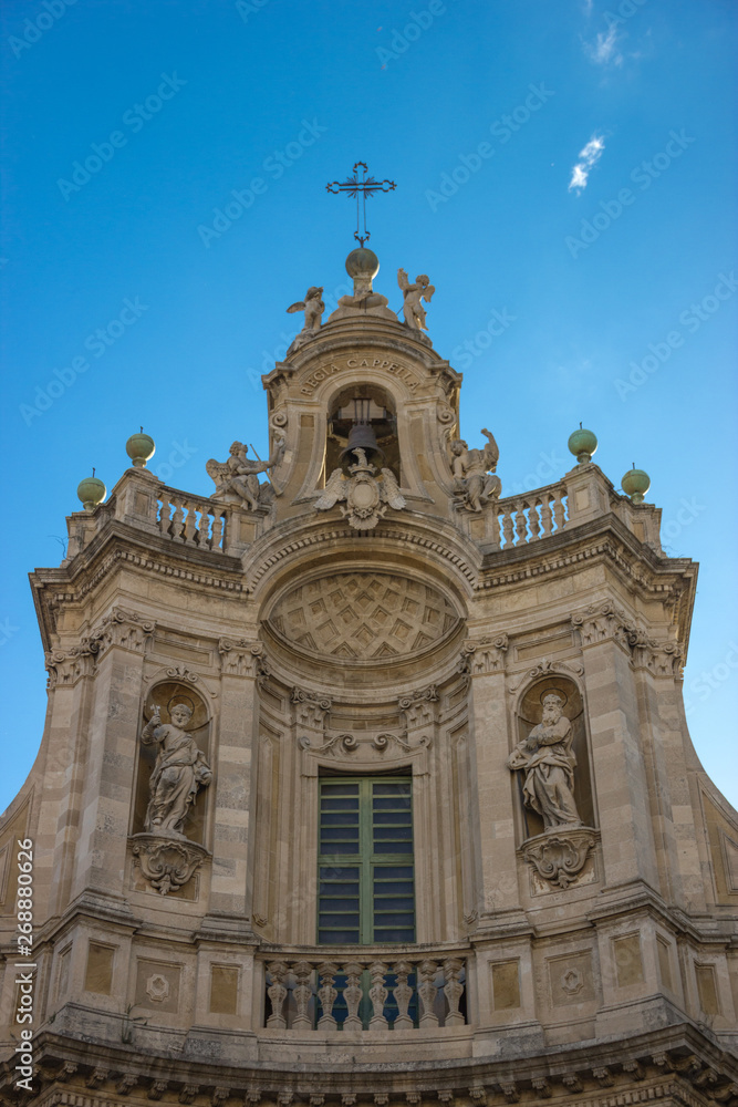 Catania baroque example in the roof of Collegita basilica, historical decorations in blue sky