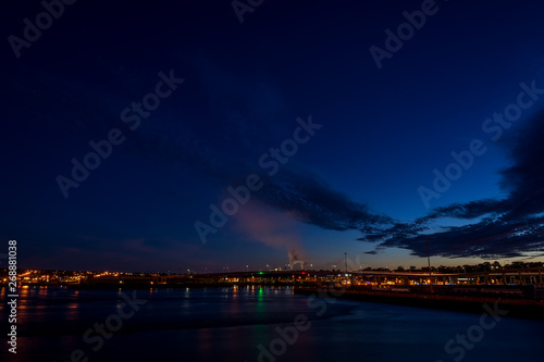 The Harbor Bridge in Saint John, New Brunswick, shortly after sunset. The sky is dark blue with some cloud, and smoke from the pulp mill is visible. The view is from across the harbor. Room for text.