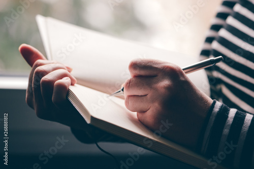 Left-handed woman writing diary