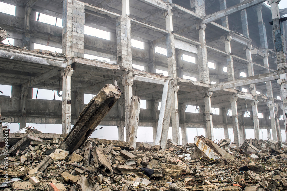 A huge concrete beam sticking out of a pile of concrete debris on the background of the destroyed frame of the building. A huge concrete beam sticking out of a pile of concrete debris on the background of the destroyed frame of the building.