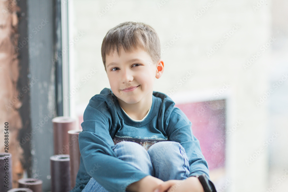 child boy sitting behind the window and smile child boy sitting behind the window and smile