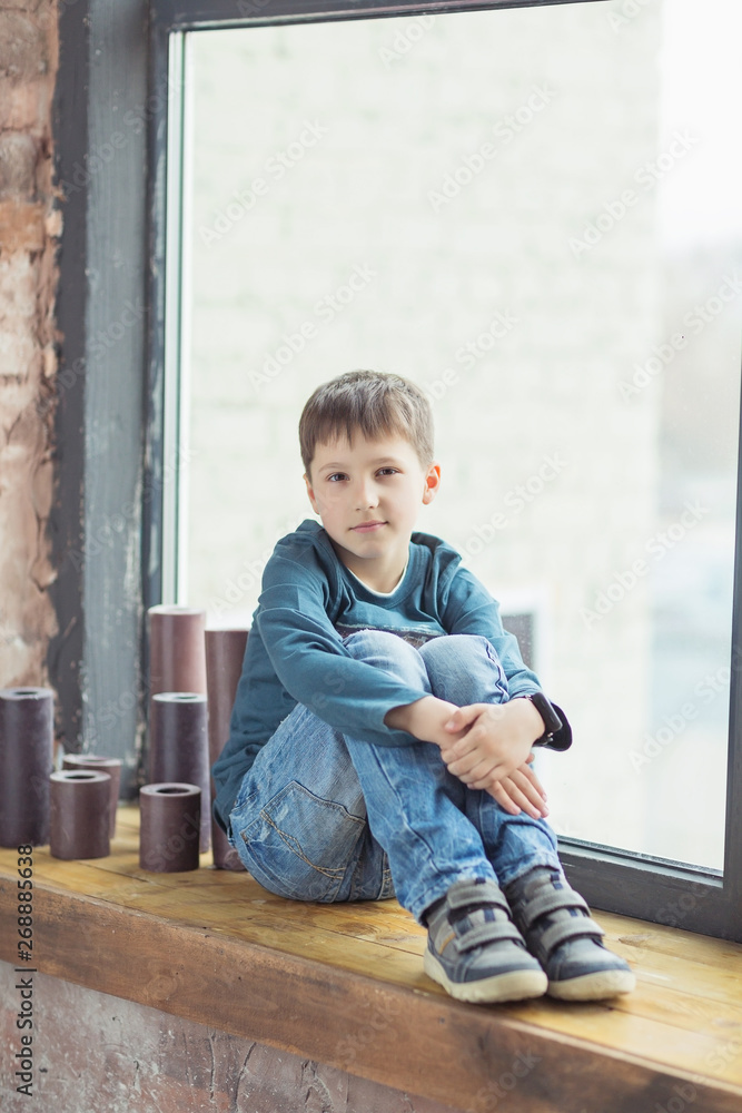 child boy sitting behind the window and smile child boy sitting behind the window and smile