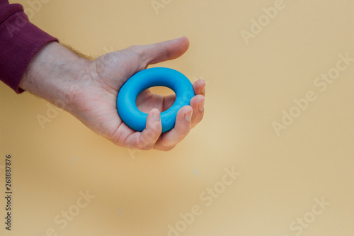 blue rubber expander in hand isolated on yellow background. photo