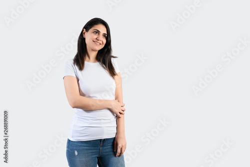 Young girl wearing blank white t-shirt and blue jeans. Grey wall background 