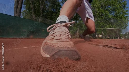 Tennis player on a clay court sliding to reach a ball