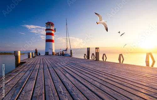 Lighthouse at Lake Neusiedl at sunset near Podersdorf with sea gulls flying around the lighthouse. Burgenland, Austria