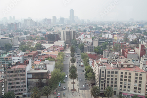 Calle vista desde el Monumento a la Revolución con la ciudad de México contaminada como fondo