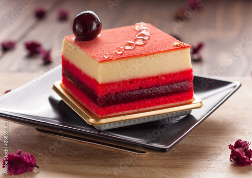 Slice of delicious berry mousse cake on wood floor photo