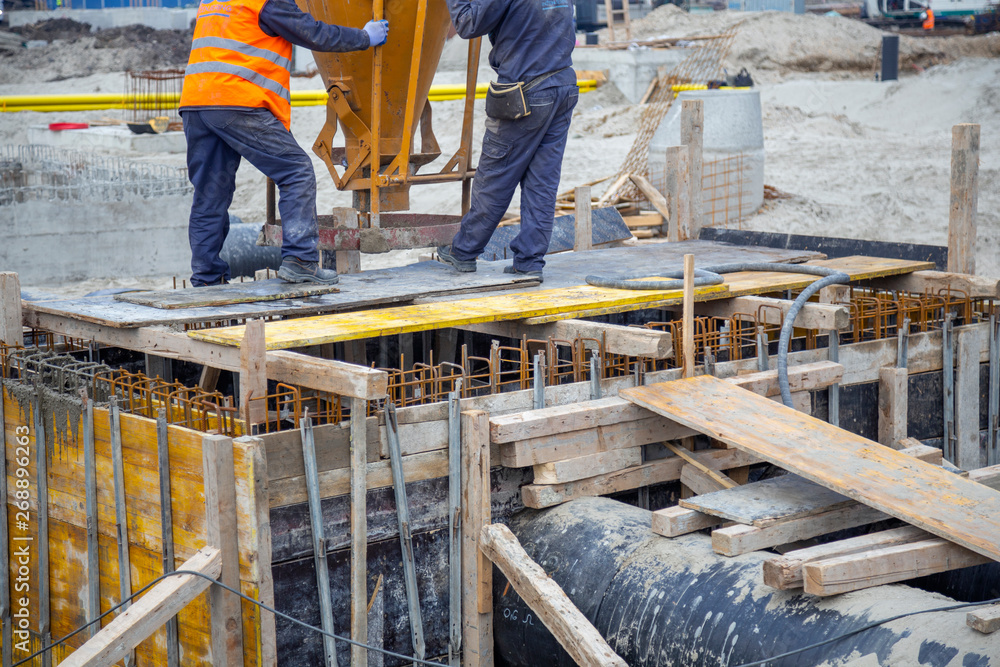 Construction workers pouring with concrete funnel skip Construction workers pouring with concrete funnel skip