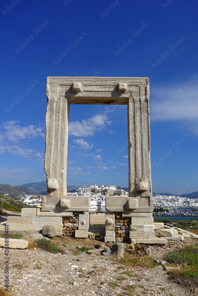 Iconic and unique Temple of Apollon or Portara (Gate) with breathtaking views to port - town and castle of Naxos island and the Aegean blue sea, Cyclades, Greece