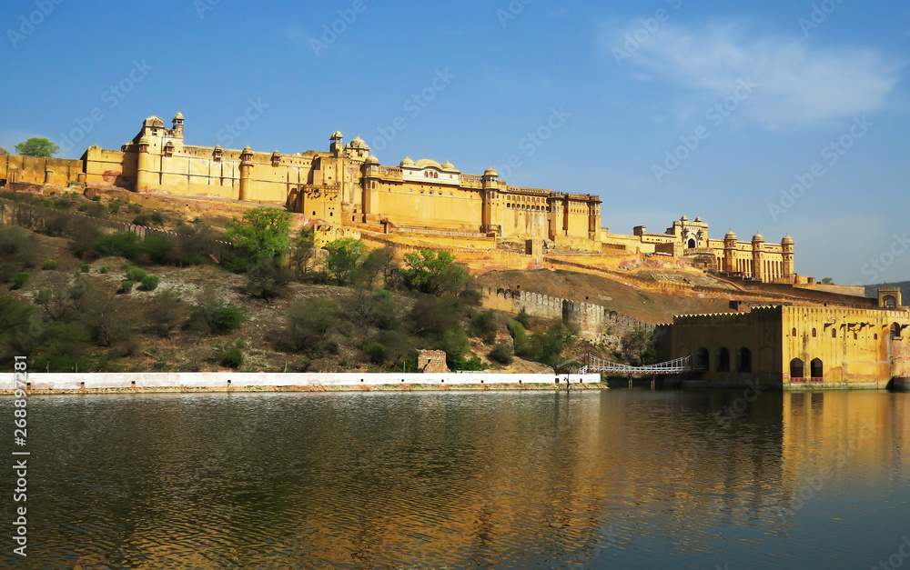Ancient Amber fort magnificent towering on a rocky hill reflected in the clear waters of the lake. Jaipur, India.