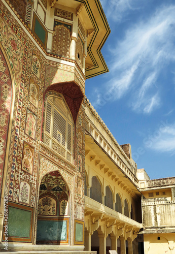 Part of the wall with paintings and carved balcony of the main palace in the ancient Amber fort. Jaipur, India.